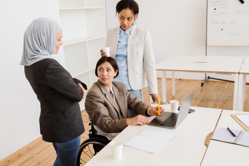 Three multiracial women discussing project while working at office