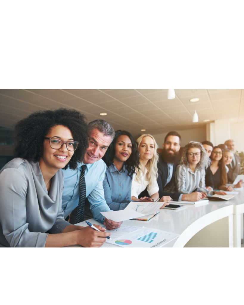 Group of diverse leaders sitting at an angled table smiling ready to start their ERG Program Management Certification course